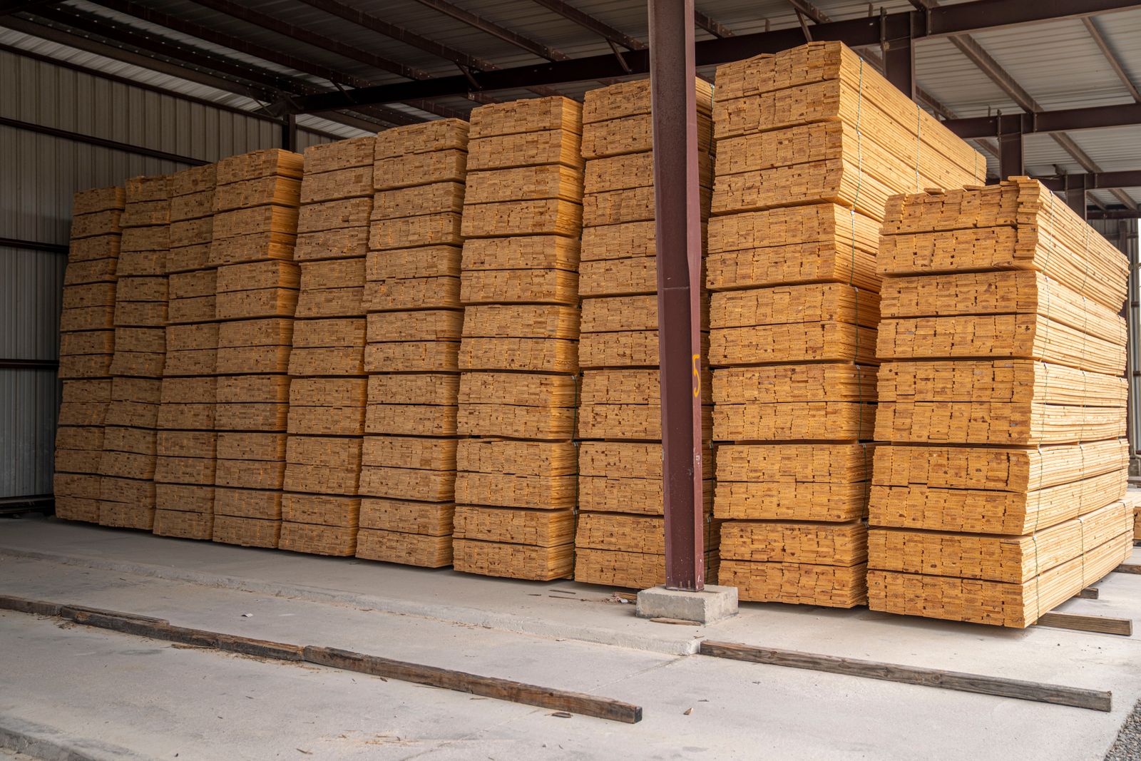 Large stacks of neatly arranged wood planks in an industrial storage facility.